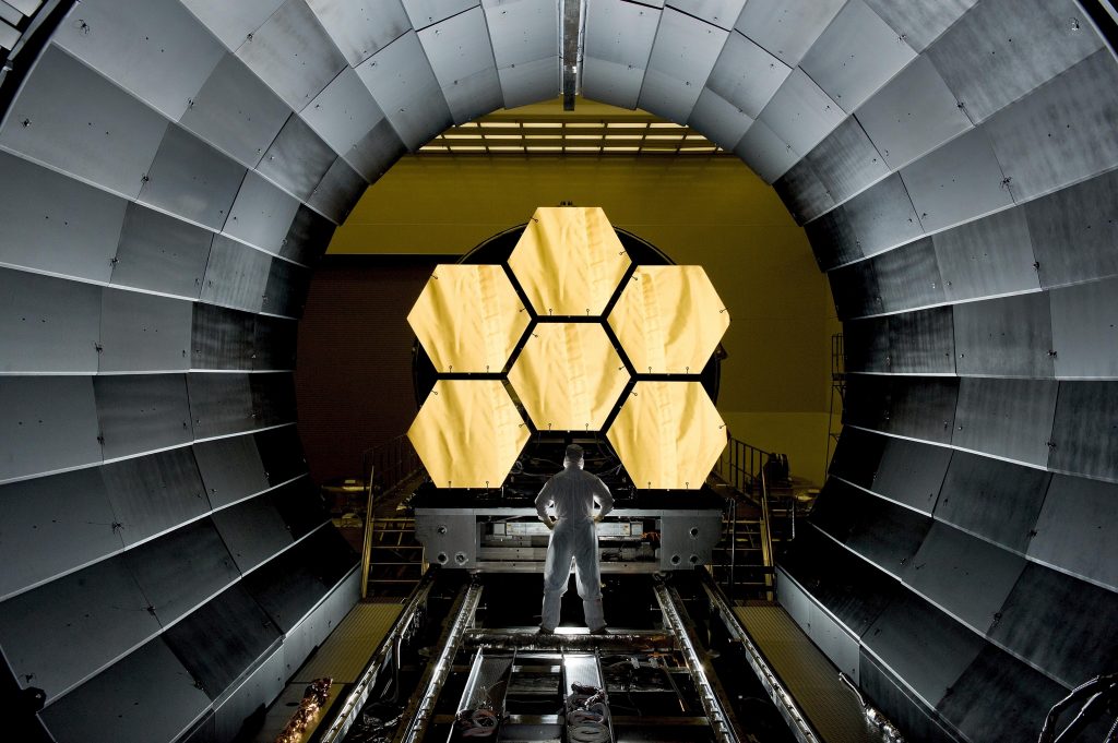 astronaut standing in front of control panel shaped like a honeycomb